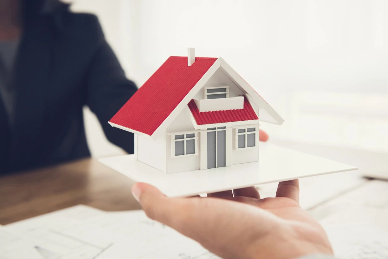 Miniature house model held over blueprints representing real estate appraisal